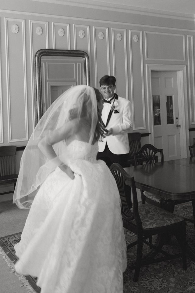 A bride and groom sharing a first look in a panelled dining room.