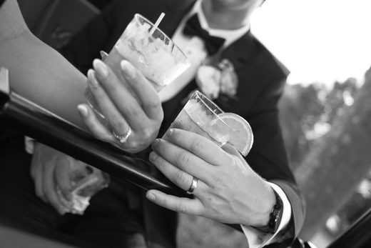 A couple clinking cocktail glasses, photographed in black and white.