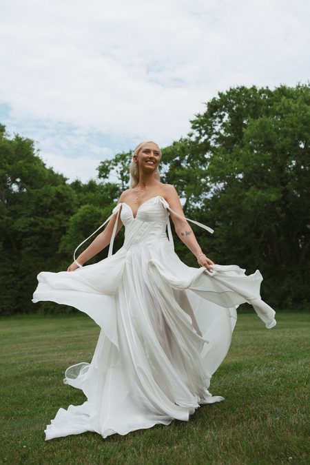Emma sweeping her skirt out across the grass during her bridal session.