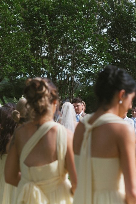 Emma’s bridesmaids in pale yellow, turning to see her for the first time.