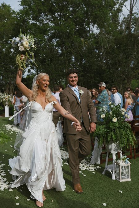 Emma and Philip walking back up the aisle as their guests cheer.