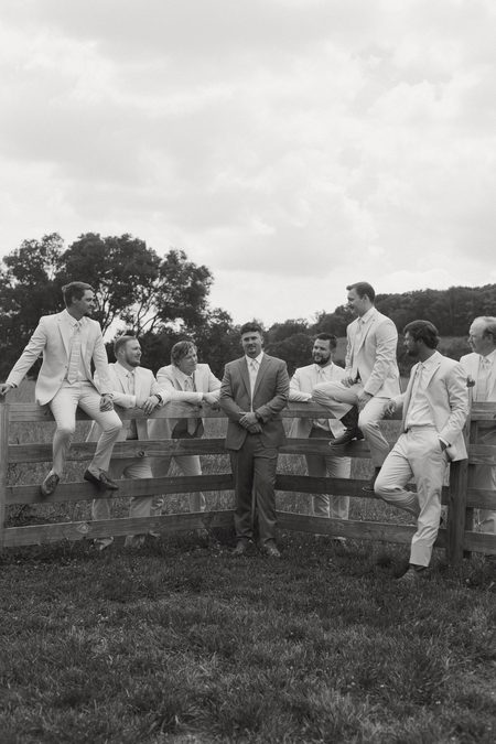 Philip and his groomsmen sitting along a fence rail, in black and white.