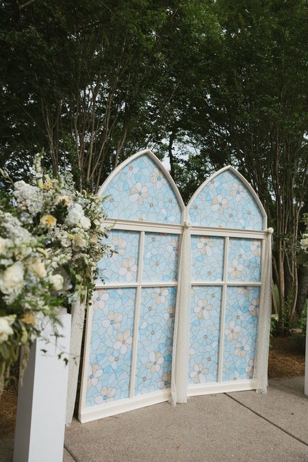 The arched stained-glass centerpiece Emma and Philip built, flanked by flowers.