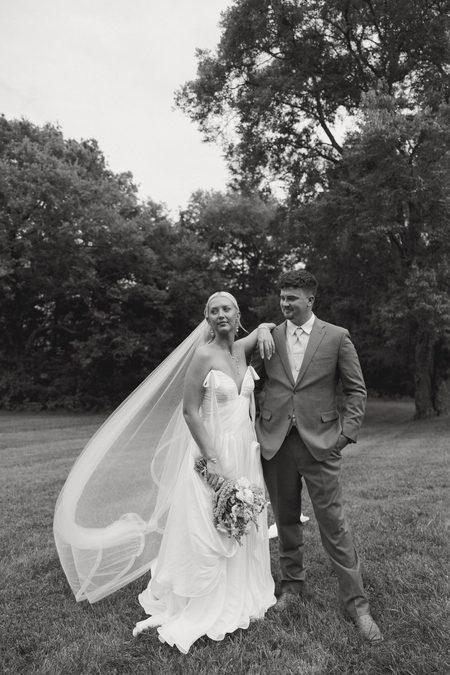 Emma and Philip standing together beneath the trees, in black and white.