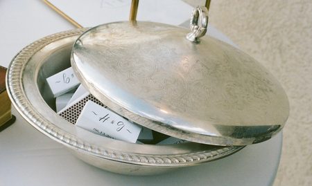 A silver cloche lifted to reveal a place card at each setting.