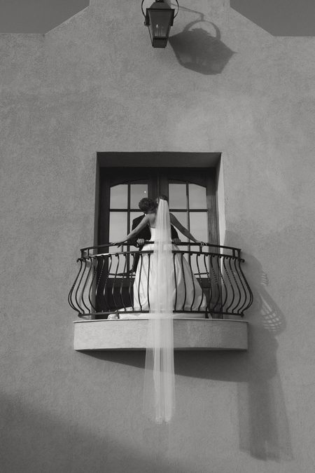 Hunter on a small balcony, her veil falling over the rail, in black and white.