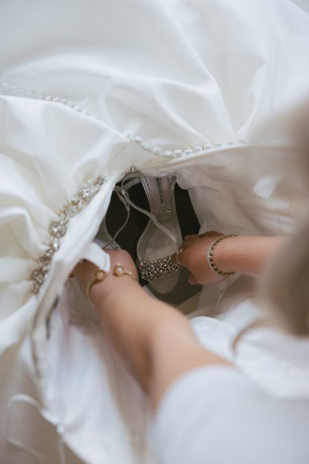 Hunter fastening her shoe beneath the hem of her gown.