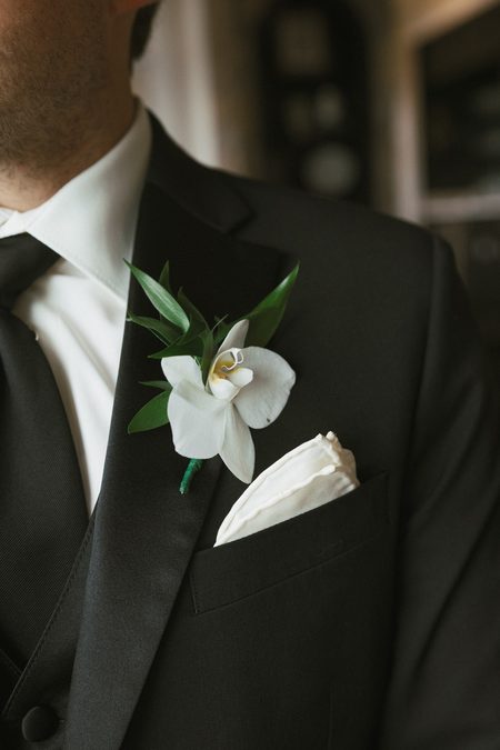 A magnolia boutonnière pinned to Gavin's lapel.