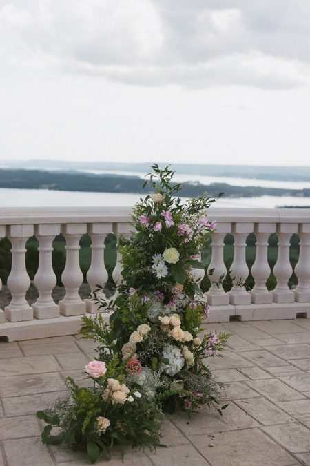 A tall arrangement of soft blooms on the balustrade above the lake.