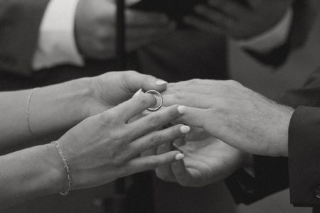 Will sliding the ring onto Kendra’s finger during the ceremony, in black and white.