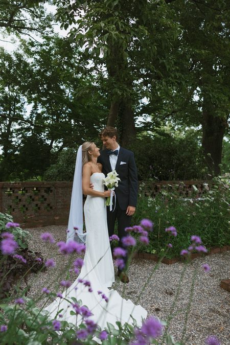 Kendra and Will together in the garden among purple blooms.