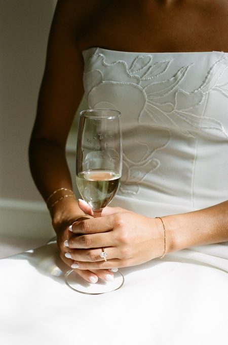 Kendra holding a glass of champagne, her rings catching the light.