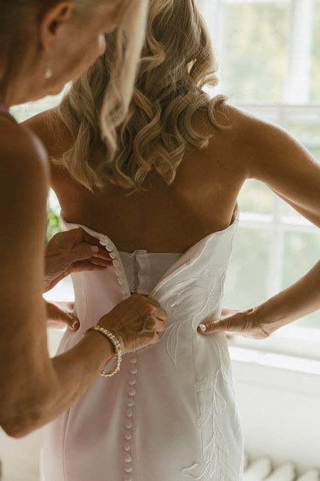 Kendra’s gown being buttoned at the back before the ceremony.