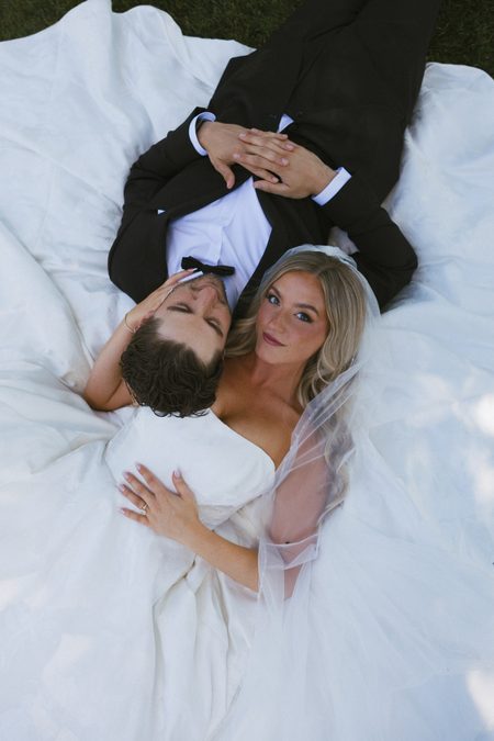 Overhead photograph of Stephanie and Nick lying together on her gown.
