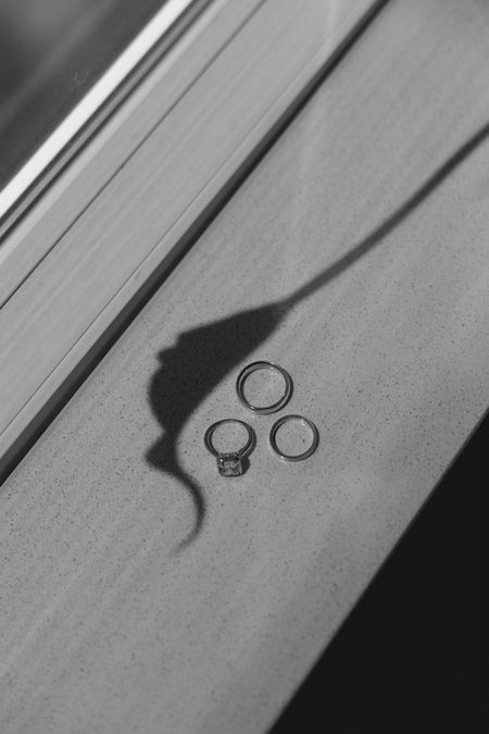 The wedding bands casting a long shadow across white linen.