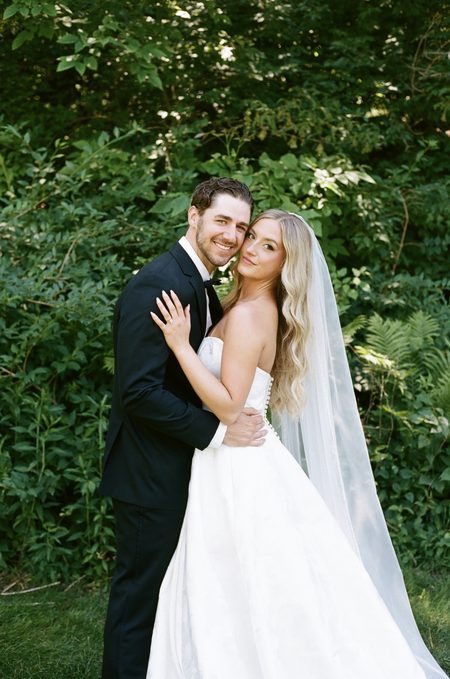 Stephanie and Nick holding one another in the greenery.
