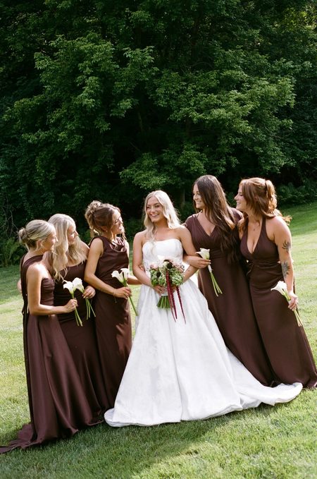 Stephanie laughing with her bridesmaids on the lawn.