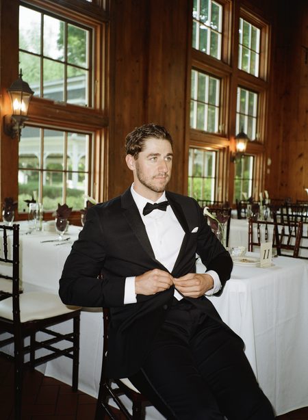 Nick fastening his tuxedo jacket in the wood-panelled carriage house.