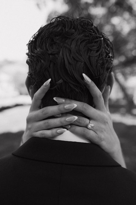Stephanie’s hands resting on the back of Nick’s neck, in black and white.