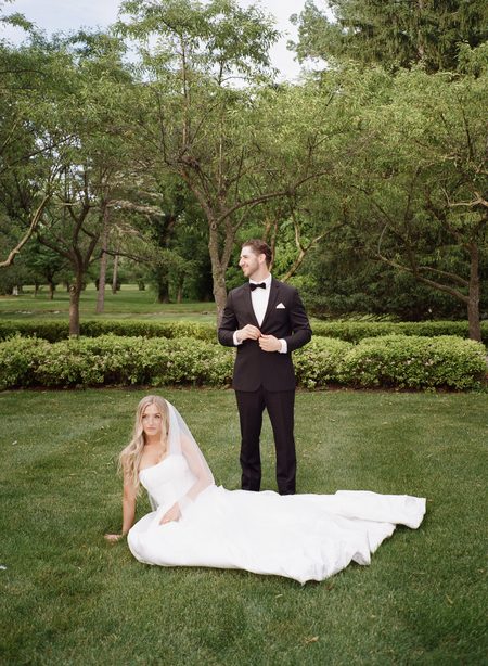 Stephanie seated on the lawn with her gown spread out beside Nick.