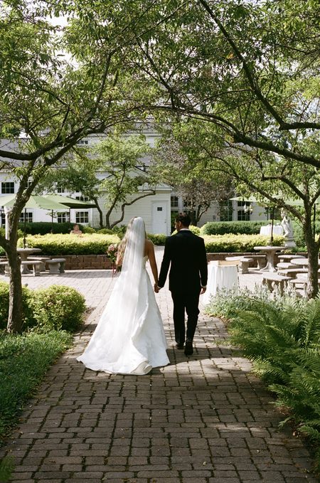 Stephanie and Nick walking hand in hand along the brick path.