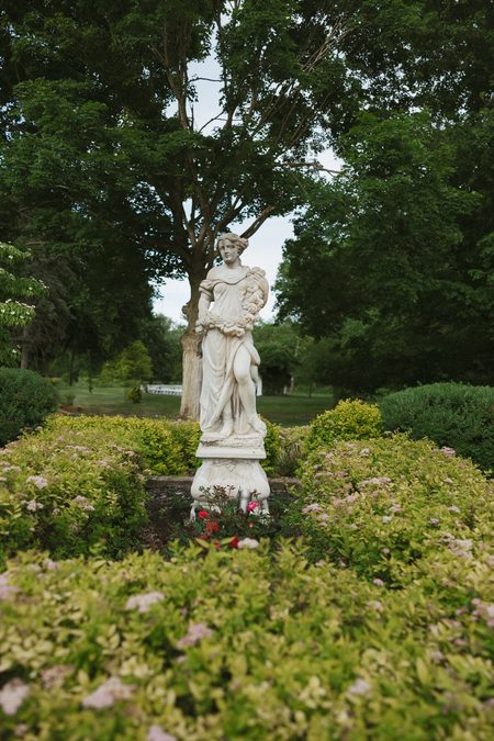 A statue and flowering borders in the gardens at Wellers Carriage House.